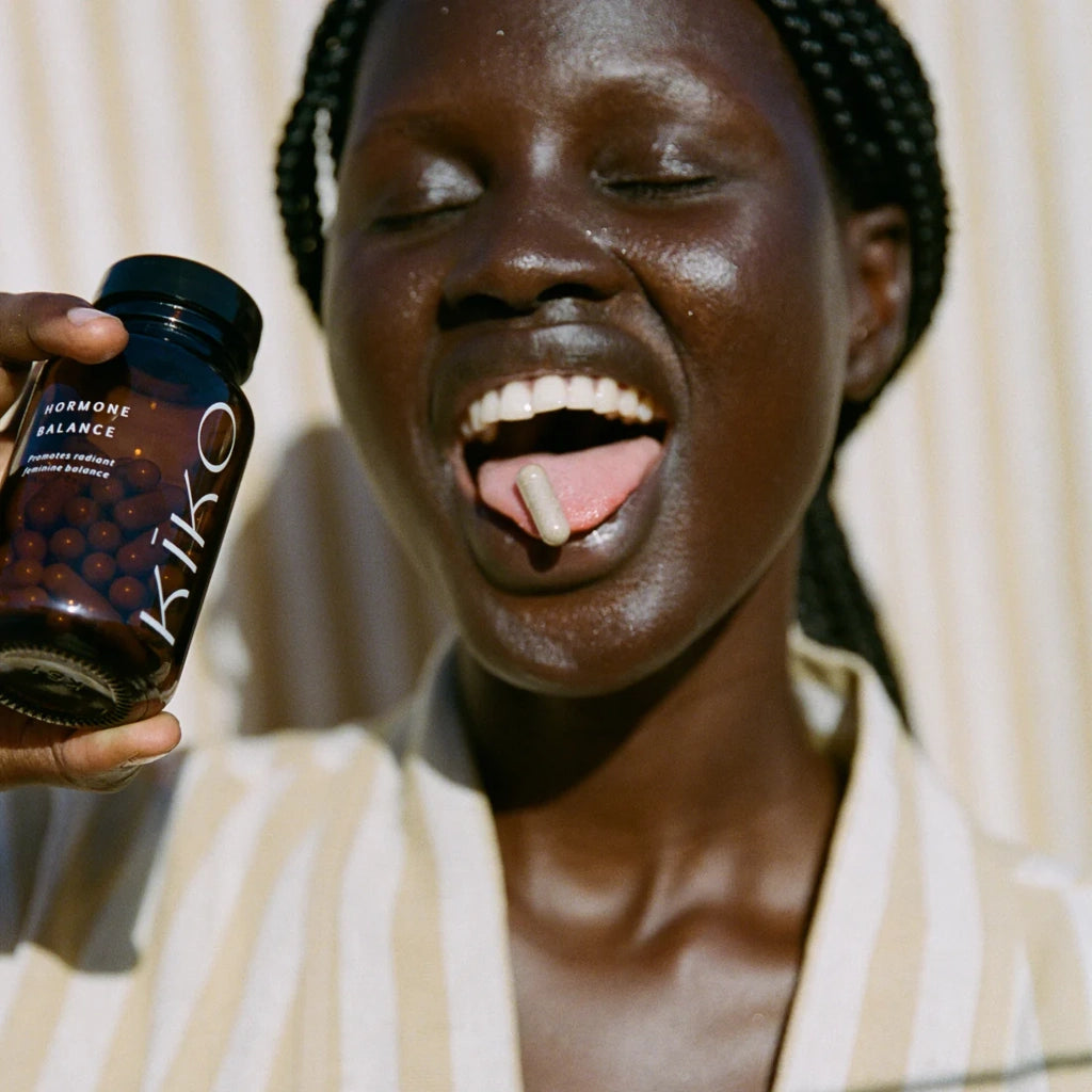 Person holding a bottle labeled 'Kiko' with a neutral background