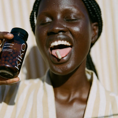 Person holding a bottle labeled 'Kiko' with a neutral background