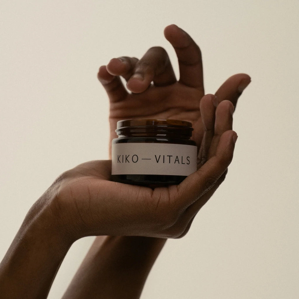 Hands holding a jar labeled 'Kiko Vitals' against a plain background