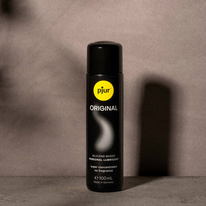 Black bottle of pjur Original lubricant with a yellow label on a gray background